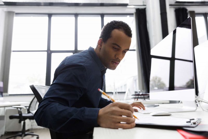 Afro american businessman making notes while sitting at his desk Afro american business man making notes while sitting at his desk