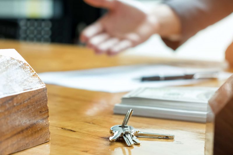 Sales are selling home. There are documents with the replica and Sales are selling home. There are documents with the replica and the keys on the table.Real estate concept.